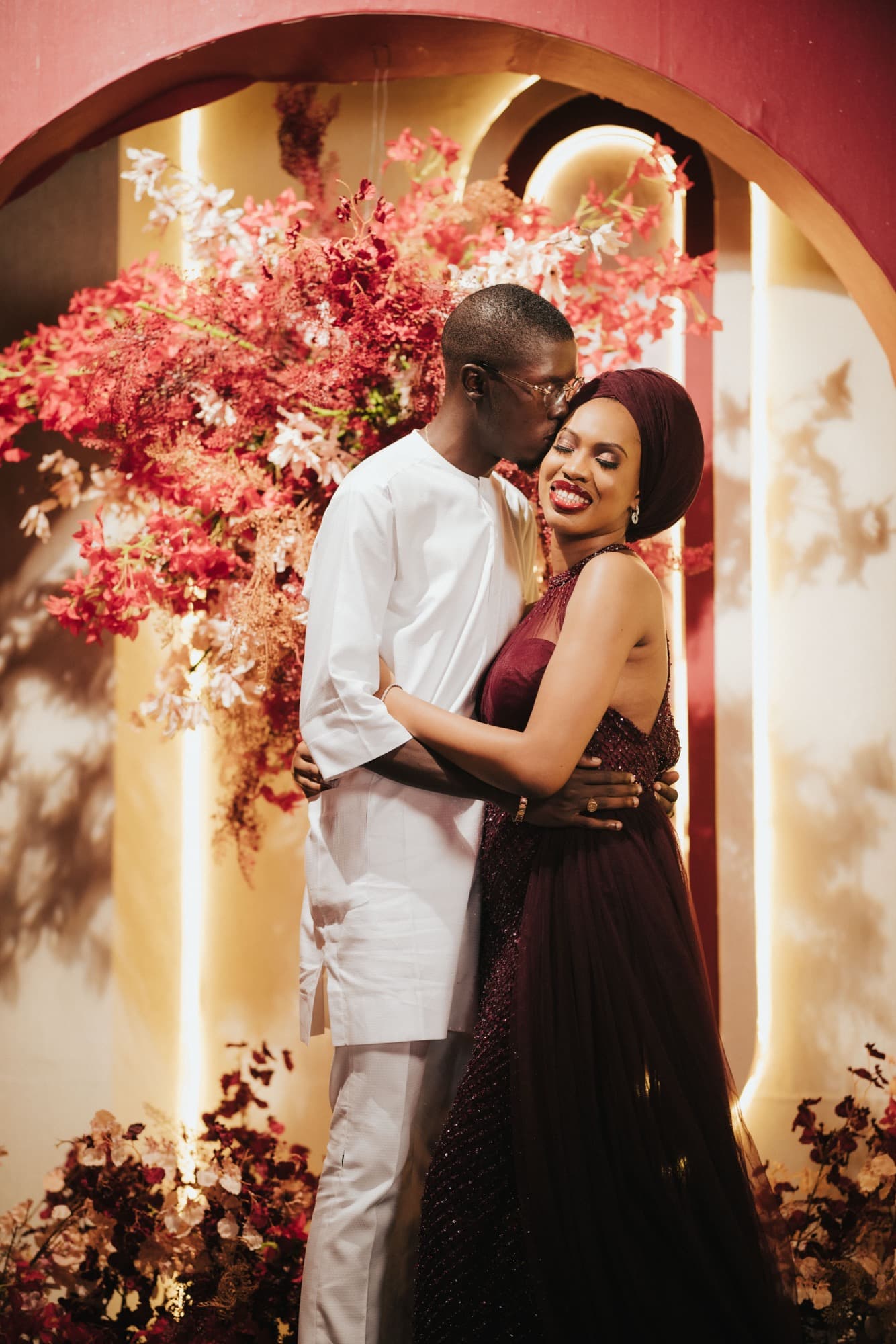 Ore, in a burgundy gown, and Esi embrace at their traditional wedding.