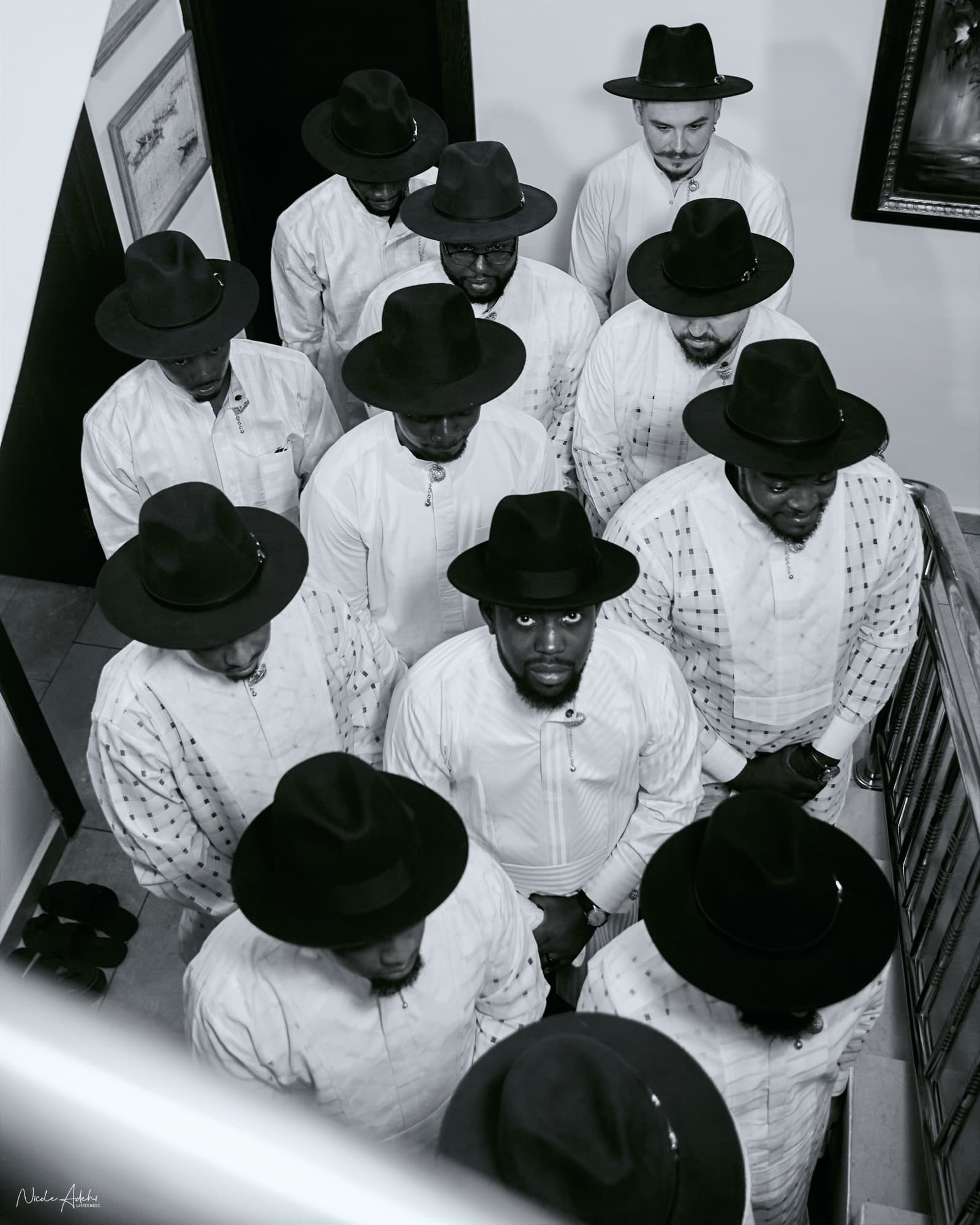 Damiete and his groomsmen in white Niger Delta attire and black fedoras, photographed from above.