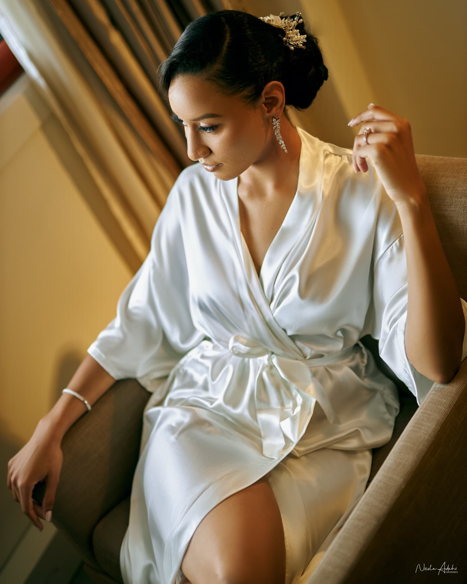 Sofia in a white robe during bridal preparations, her earrings and hairpiece in place.