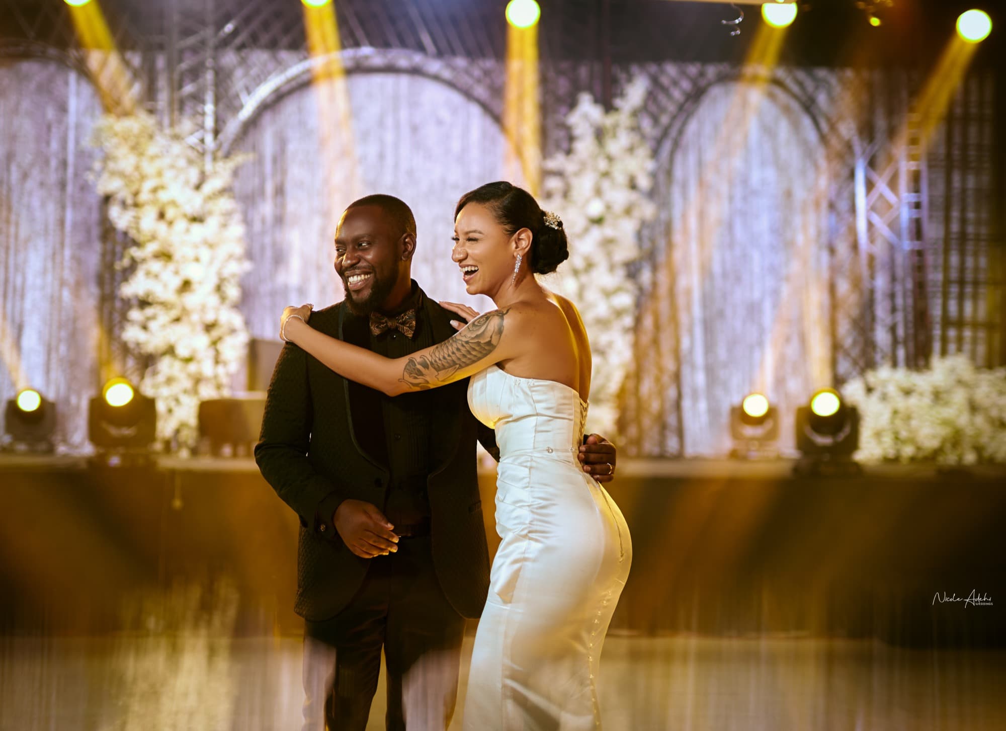Sofia and Damiete share their first dance beneath a lit floral arch.
